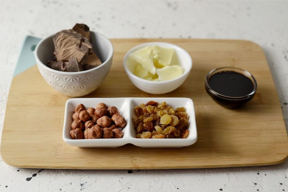 Conjunto de ingredientes tradicionais do café da manhã ou lanche doce, dispostos em pequenas tigelas sobre uma tábua de madeira.