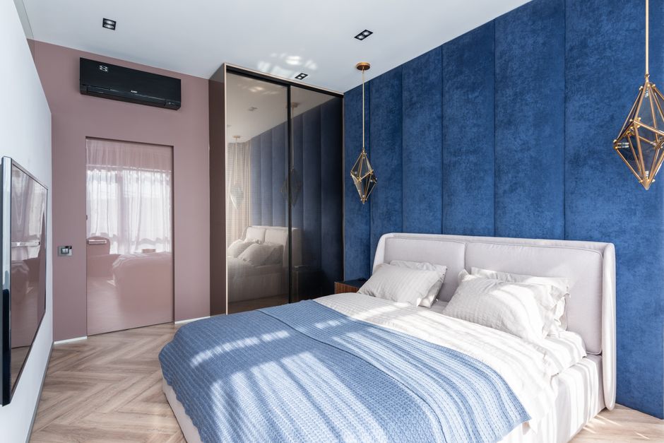 Quarto moderno com decoração azul e rosa, iluminação charmosa e espaço bem organizado, ideal para relaxamento e descanso.