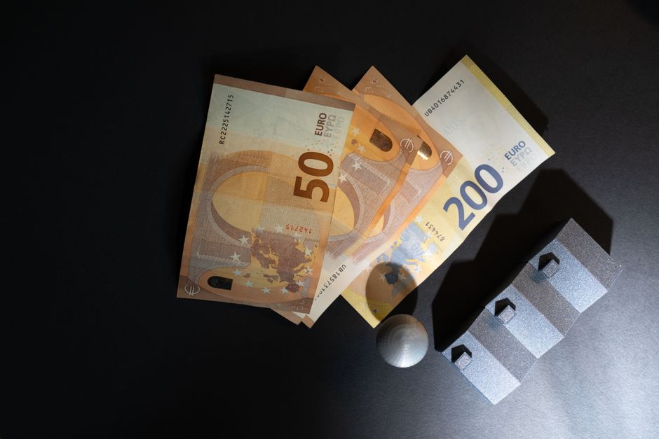 Notas de euro e uma bola de golfe sobre uma mesa escura, com objetos que criam sombras e refletindo temas de negócios e estratégia.