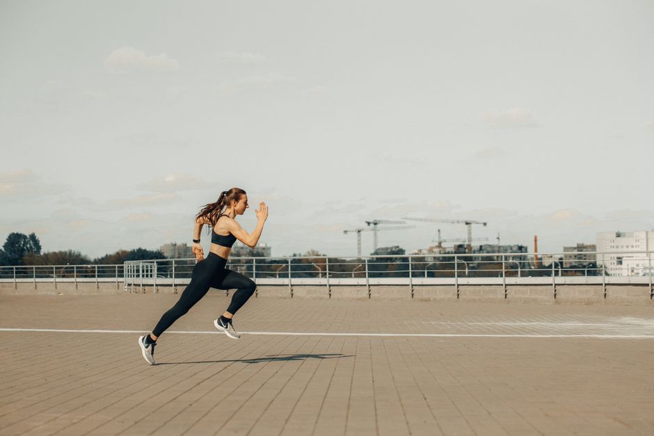 Mulher praticando corrida ao ar livre em ambiente urbano, simbolizando saúde e bem-estar.