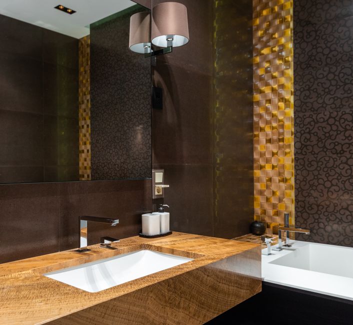 Banheiro moderno com revestimentos elegantes e iluminação discreta, ideal para ambientes de hotel ou espaço de lazer de alto padrão.
