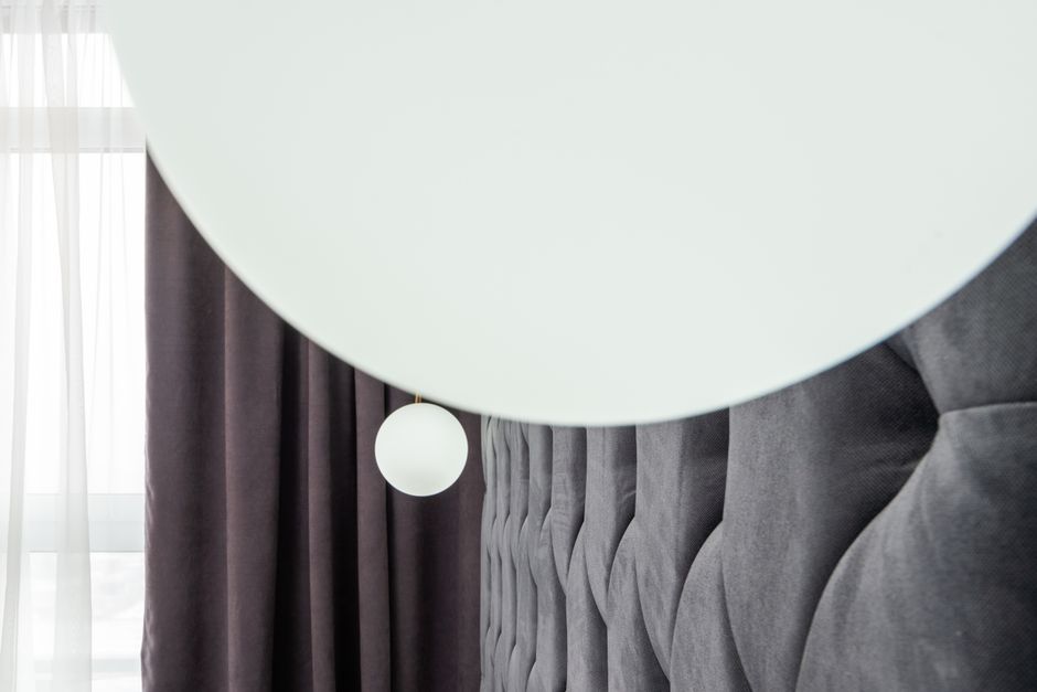 Imagem de ambiente interno com cortinas escuras, cabeceira de cama e luminária pendente, ideal para artigos sobre decoração de quarto ou design de interiores.