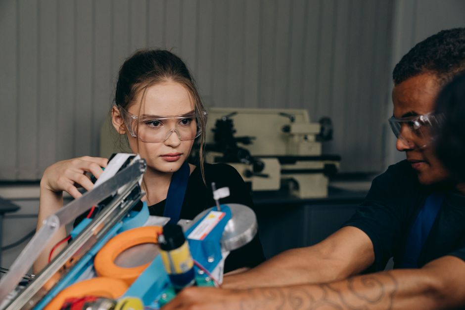 Jovens engenheiros ou estudantes de tecnologia trabalhando juntos em um laboratório de robótica ou projeto de inovação.