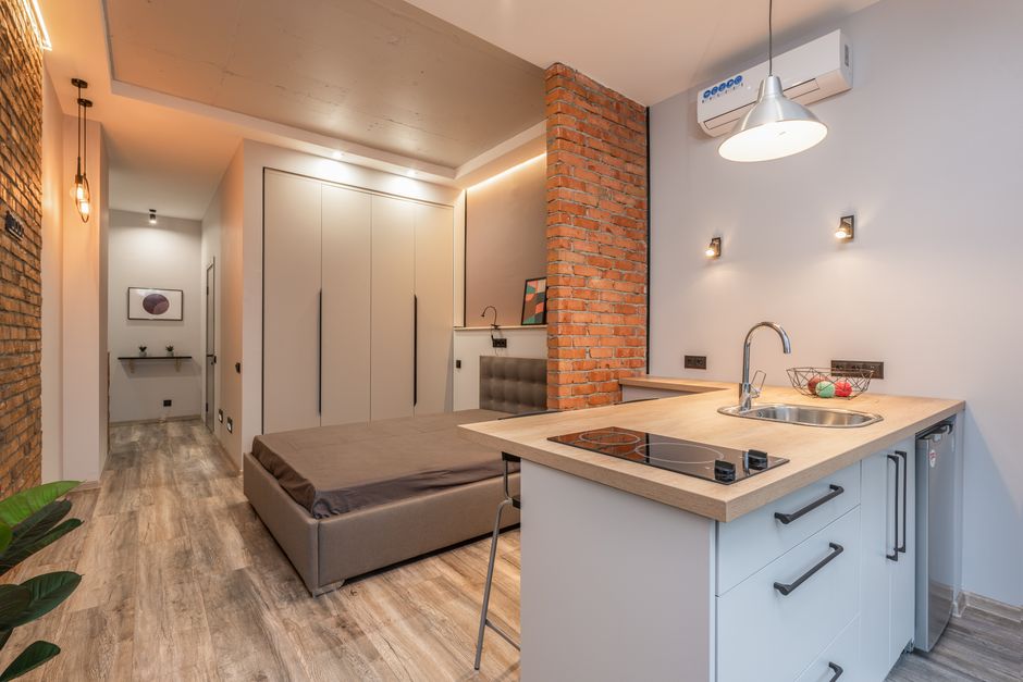 Imagem de um espaço compacto e moderno que combina uma área de convivência e cozinha integrada com elementos de design minimalista e industrial, destacando a estética do apartamento compacto.