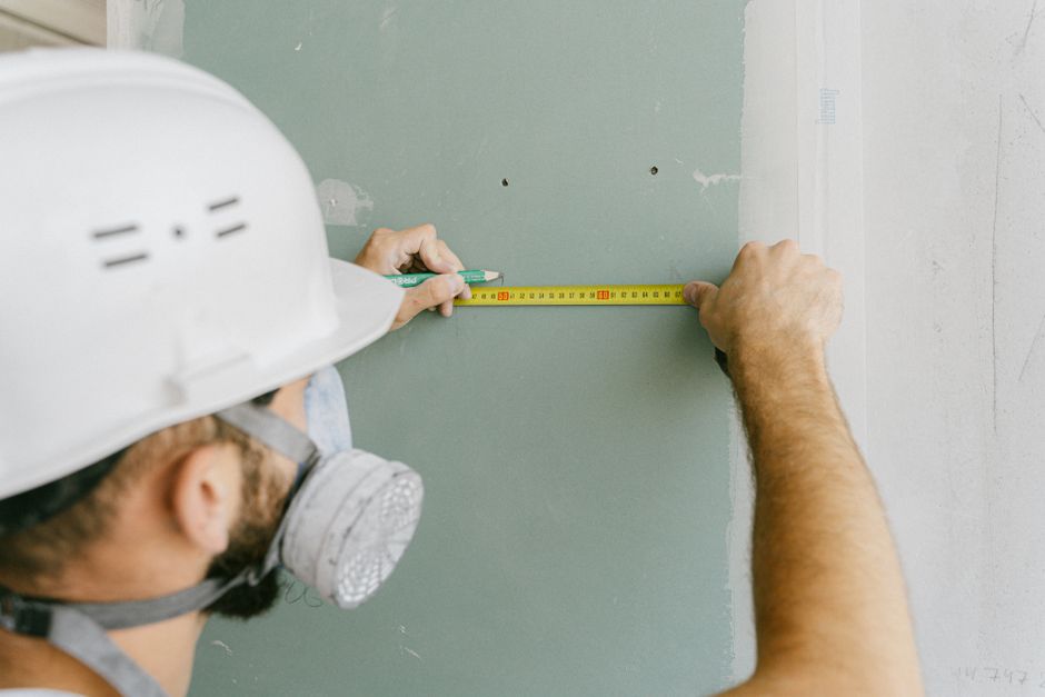 Profissional de construção civil medindo uma parede para futuras obras ou ajustes na obra de construção.
