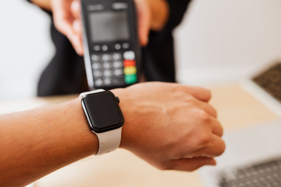 Pessoa realizando pagamento com cartão de crédito usando smartwatch, evidenciando inovação tecnológica em transações financeiras.