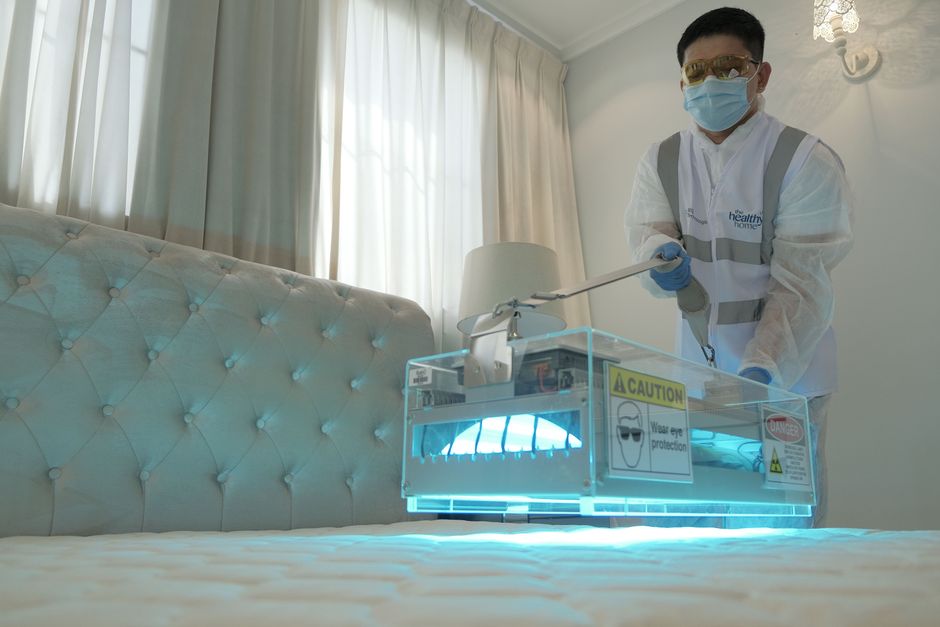 Profissional usando equipamento de desinfecção em um ambiente interno, representando cuidados e higiene em espaços de saúde ou hotéis.