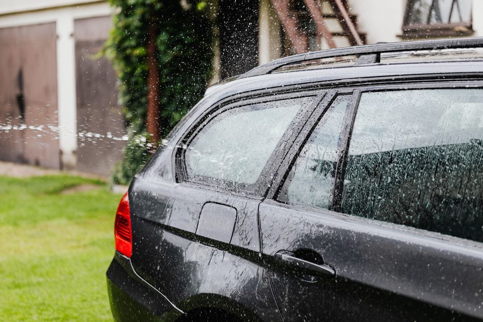 Imagem de um carro sendo lavado ao ar livre, destacando o ato de higiene automotiva.
