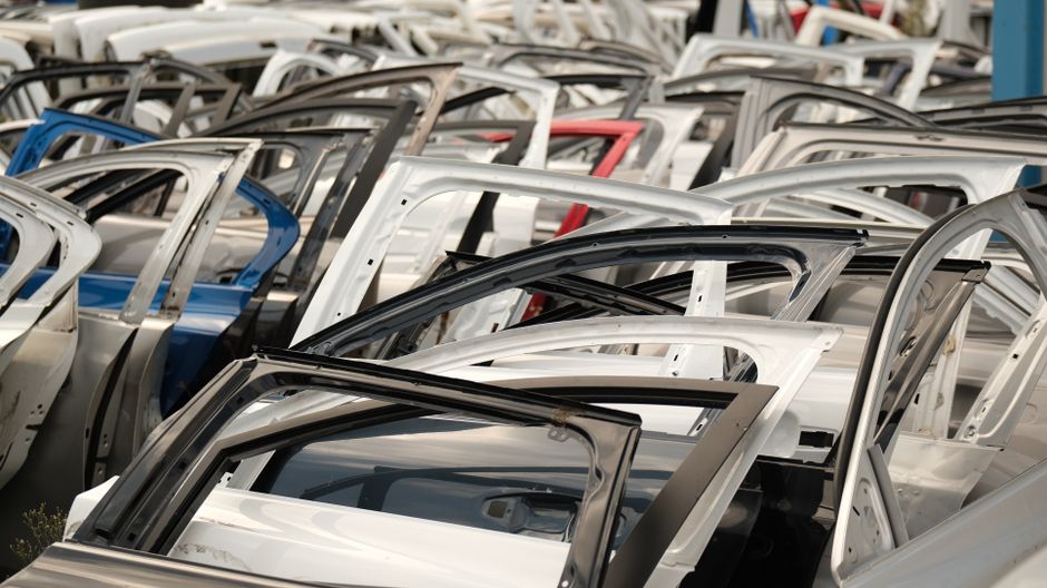 Imagem de várias estruturas de portas de automóveis empilhadas em uma fábrica ou depósito, destacando o setor de fabricação de veículos.
