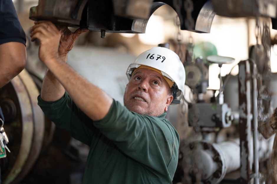 Homem trabalhando em manutenção industrial, demonstrando atenção e esforço em ambiente de fábrica ou usina.