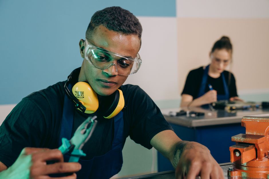 Jovem mulher realizando um trabalho técnico com ferramentas, simbolizando prática em área de engenharia ou manutenção.