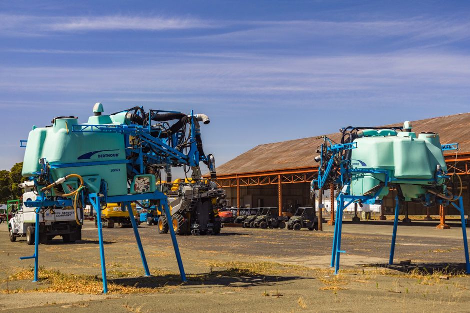 Duas máquinas agrícolas gigantes em um depósito ao ar livre, prontas para uso na agricultura de alta tecnologia.