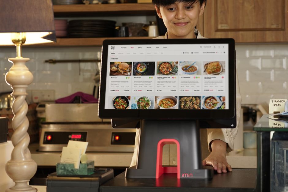 Funcionária de restaurante usando um sistema de soma de pedidos digital para gerenciar pedidos de comida.