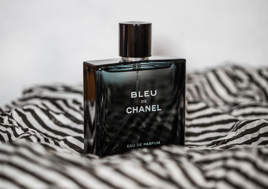 Imagem de um frasco de perfume Bleu de Chanel repousando sobre uma roupa com estampa de zebra, evocando elegância e estilo.