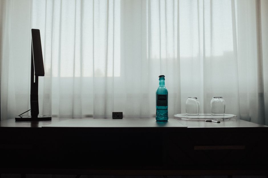 Imagem de uma mesa de trabalho minimalista com um monitor, uma garrafa de água e dois copos, indicando um espaço de trabalho ou estudo limpo e organizado.