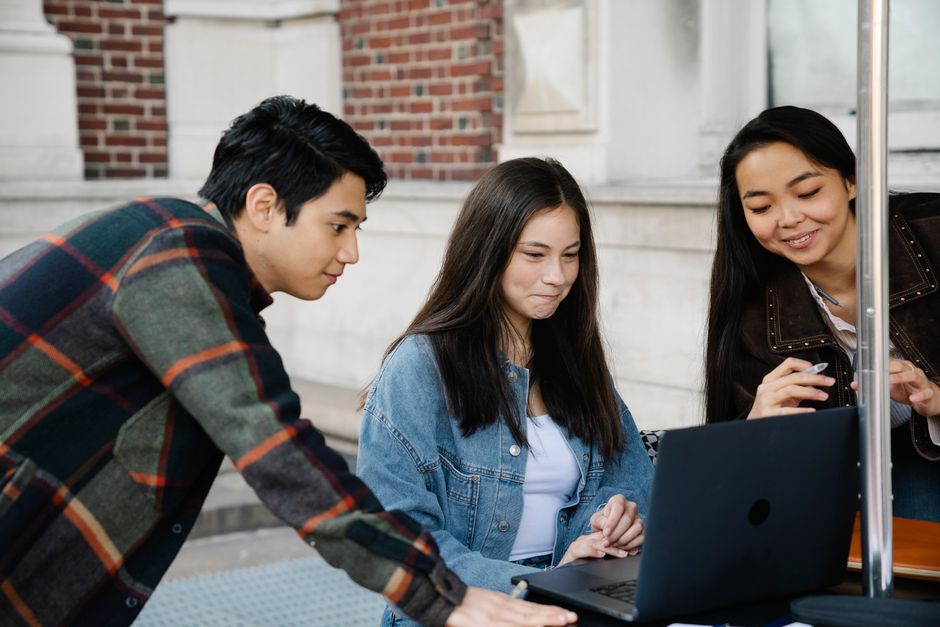 Grupo de jovens compartilhando informações e interagindo em ambiente ao ar livre, representando colaboração e tecnologia educativa.