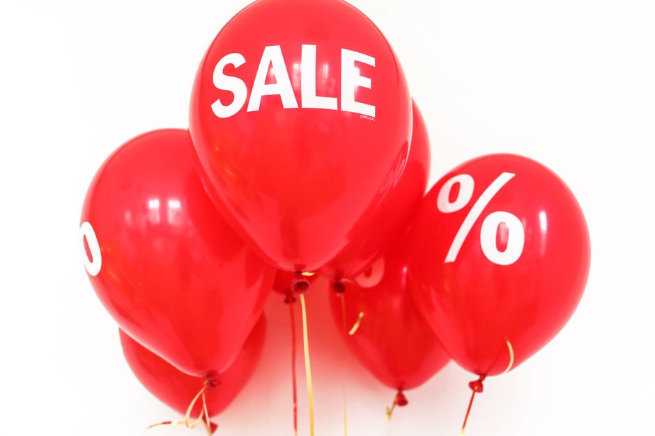 Balões vermelhos com mensagens de promoção e desconto, simbolizando uma liquidação ou oferta especial.