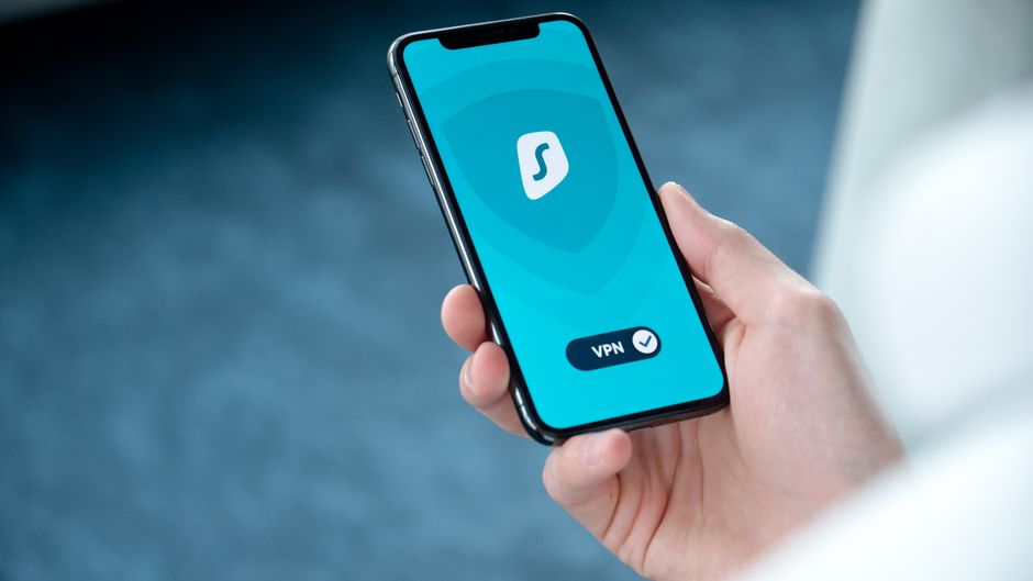 Pessoa segurando um smartphone exibindo um aplicativo de VPN, ilustrando segurança digital e privacidade online.