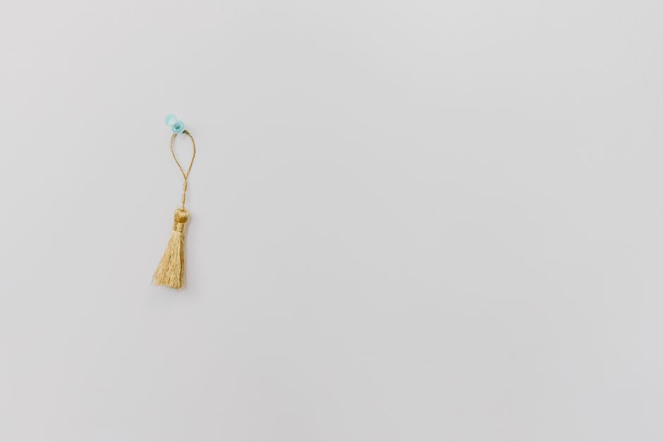 Imagem minimalista de um pingente decorativo com tassel, simbolizando simplicidade e delicadeza, ideal para ilustrar temas de decoração, estilo de vida ou bem-vindo ao blog.