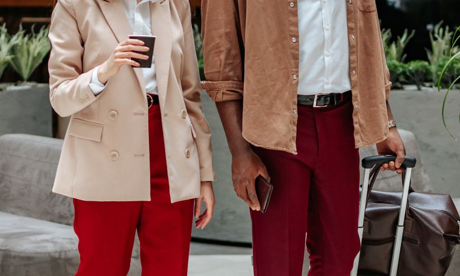 Homens e mulheres de negócios em ambiente corporativo, prontos para reunião ou viagem de trabalho, com trajes formais e bagagem de mão.