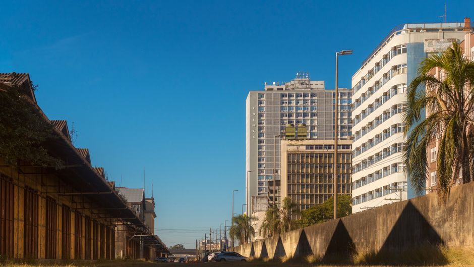 Imagem de uma área urbana com prédios residenciais e comerciais sob céu claro e ensolarado, ideal para artigos sobre planejamento urbano ou vida na cidade.