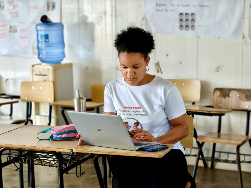 Juventude estudando com foco na escola, usando computador em sala de aula, com atenção aos estudos.