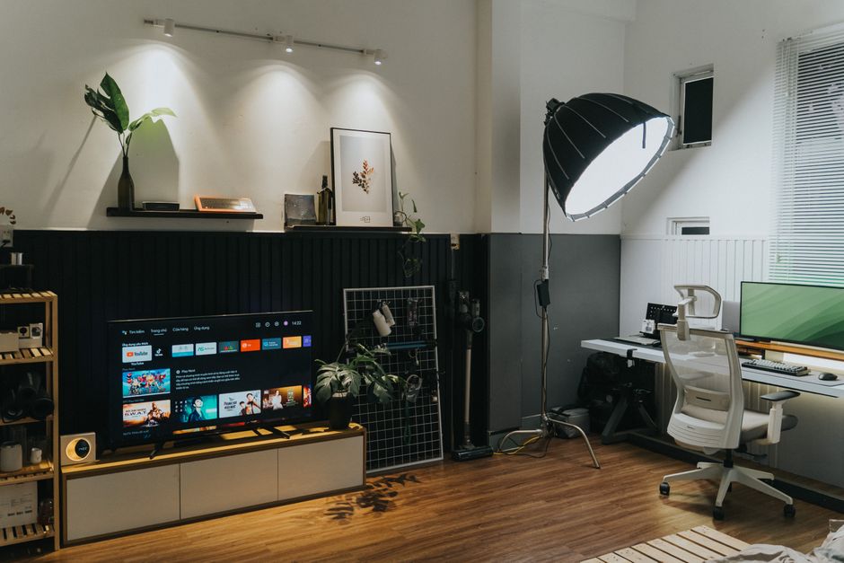 Imagem de um ambiente de escritório com iluminação de estúdio, incluindo um espaço de trabalho com computador, iluminação profissional e elementos decorativos modernos.