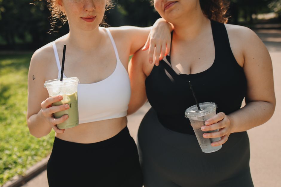 Duas mulheres com roupas esportivas desfrutando de um momento ao ar livre, simbolizando amizade e bem-estar.