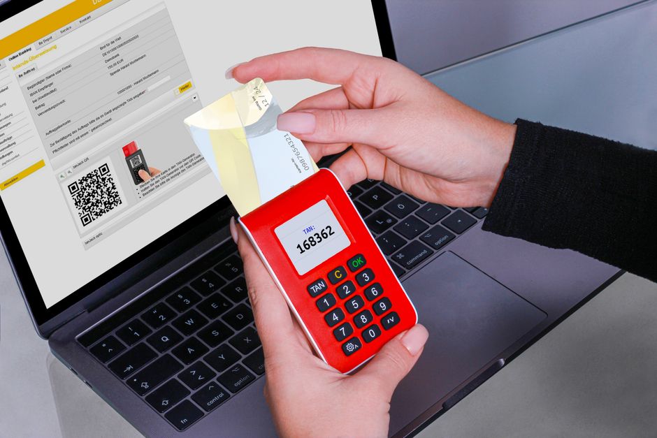 Pessoa realizando pagamento com cartão de crédito por aproximação utilizando dispositivo eletrônico conectado ao computador, representando o tema de pagamentos digitais e comércio eletrônico.