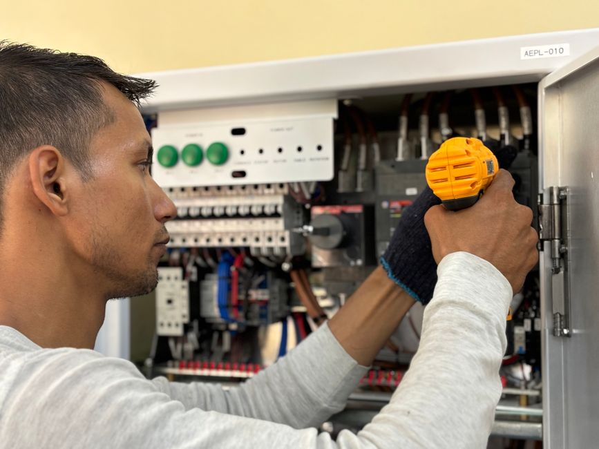 Profissional realizando manutenção em painéis elétricos, simbolizando técnicas de instalação elétrica e manutenção industrial.
