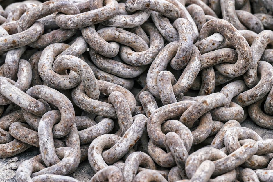 Correntes de ferro envelhecidas empilhadas, simbolizando resistência e obstáculos.