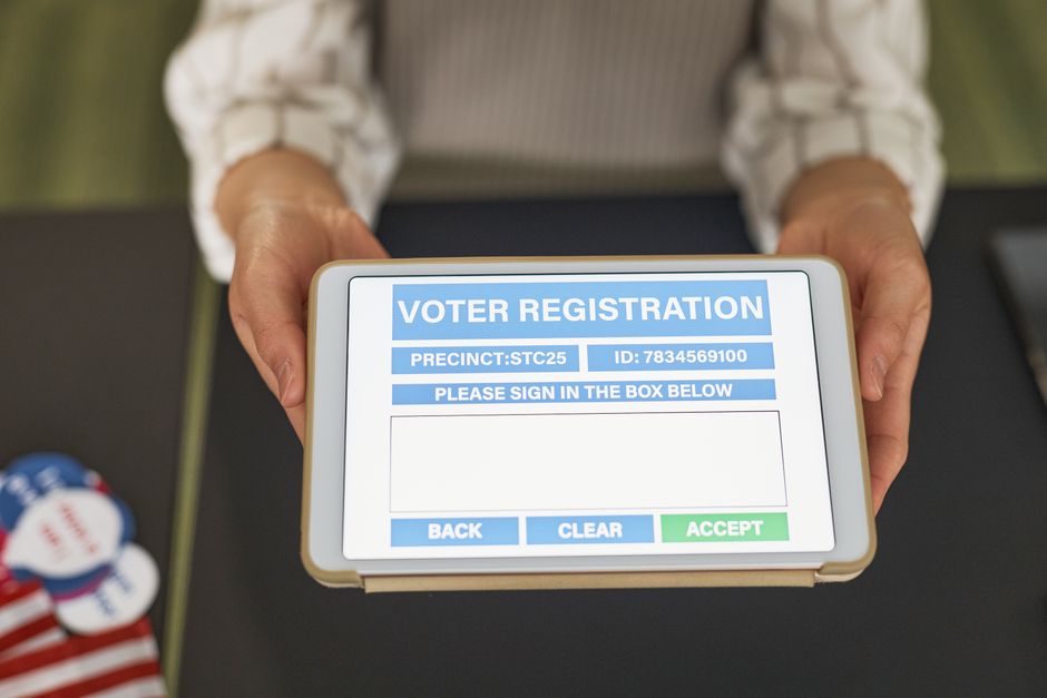 Imagem de uma pessoa segurando um tablet com tela de registro de votação digital, destacando o tema de processos eletrônicos e participação cidadã.