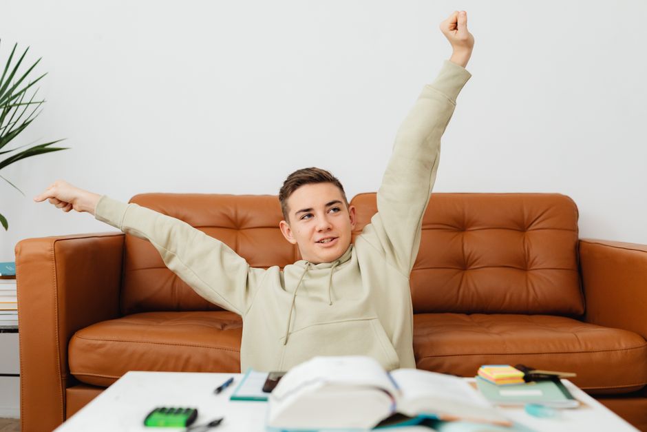 Jovem demonstrando entusiasmo e motivação em um ambiente de estudo ou trabalho, simbolizando conquista e crescimento pessoal.
