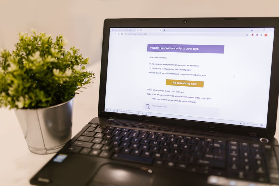 Imagem de um laptop aberto exibindo uma mensagem de aviso de cartão de crédito, ao lado de uma planta decorativa, ideal para artigos sobre segurança financeira online.