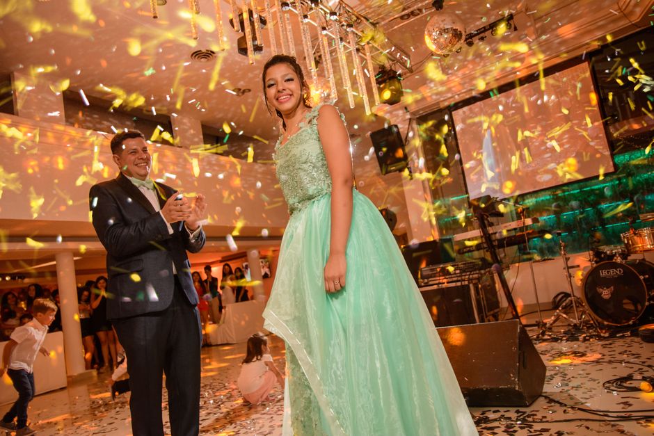 Celebrando uma ocasião especial com uma mulher sorridente em um evento festivo, com iluminação colorida e decoração brilhante no ambiente.