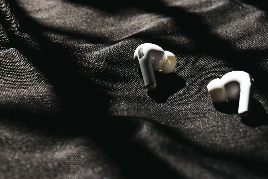 Fone de ouvido sem fio sobre um tecido escuro, simbolizando tecnologia e conexão.