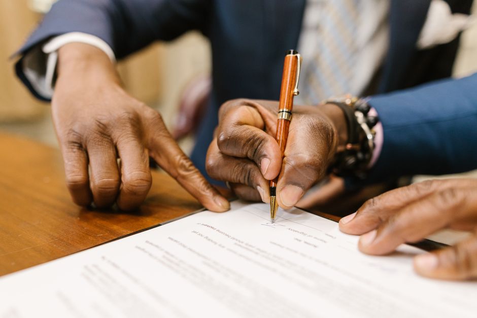 Homens assinando um documento importante, simbolizando acordo ou contratação empresarial.
