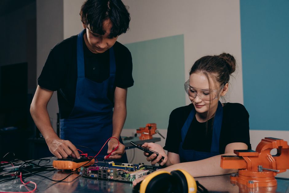 Duas pessoas trabalhando em um projeto de eletrônica ou tecnologia, demonstrando colaboração e inovação.