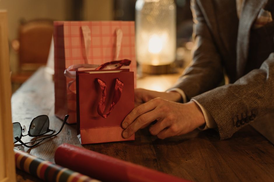 Homem preparando uma surpresa com embrulhos de presentes em um ambiente acolhedor, ideal para artigos sobre celebrações, datas comemorativas ou gerenciamento de eventos especiais.