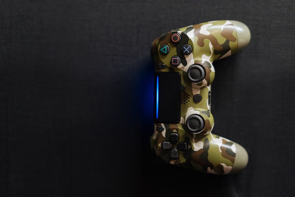 Controle de videogame com capa de camuflagem sobre uma superfície escura, representando o tema de entretenimento digital.