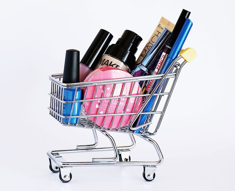 Imagem de uma minicesta metálica de compras contendo diversos produtos de beleza e cuidados pessoais, ideal para ilustrar dicas de beleza ou cuidados diários.