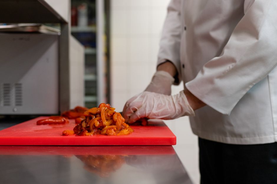 Pessoa preparando alimentos na cozinha, evidenciando o processo de culinária ou gastronomia.