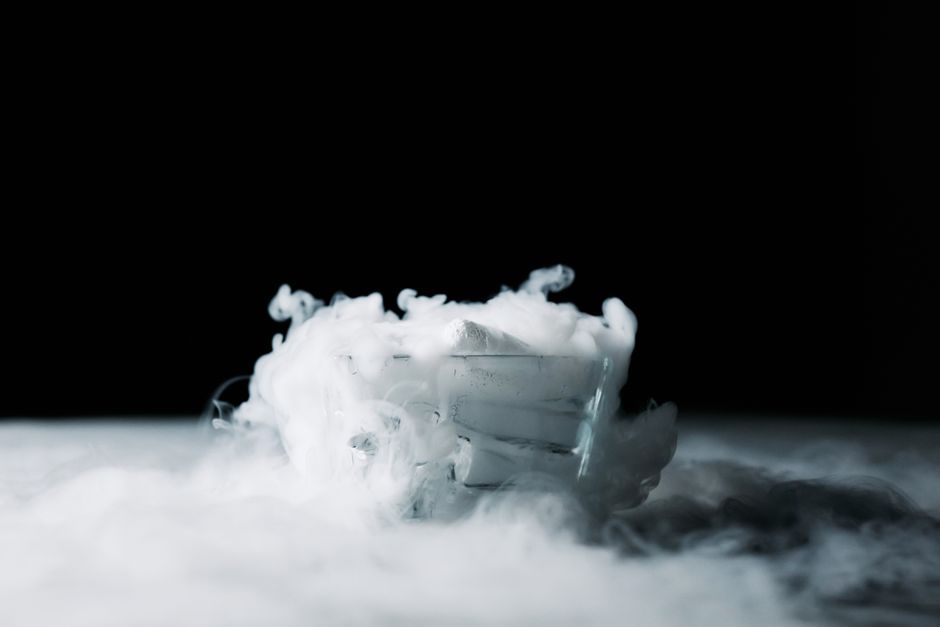 Uma tigela branca com fumaça ou névoa azulada emergindo, criando um efeito misterioso e dramático em um fundo preto, com foco na atmosfera enigmática.