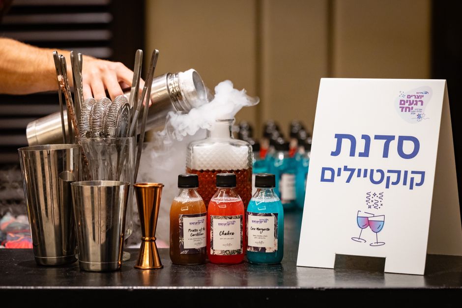 Imagem de uma estação de coquetel com ingredientes coloridos e equipamentos, destacando uma festa ou celebração com temática de drinks.