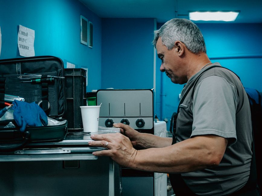Homem realizando manutenção ou inspeção técnica em um ambiente de trabalho, cercado por ferramentas e equipamentos.