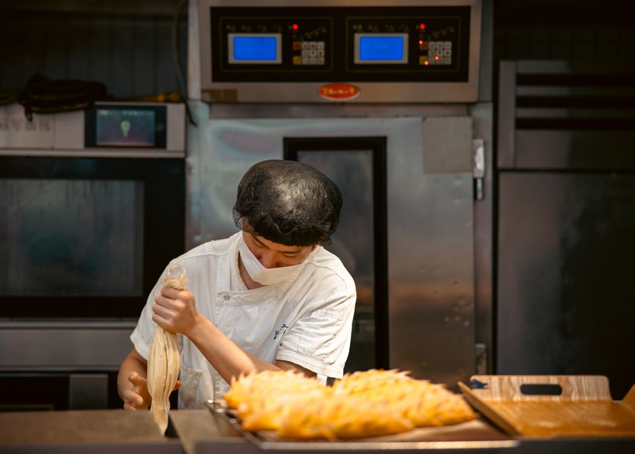 Chef preparando uma peça de massa em uma cozinha industrial, focada na arte da gastronomia e culinária profissional.