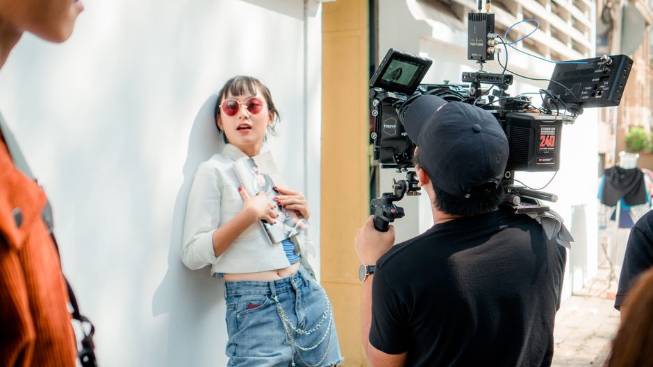 Jovem realizando uma sessão de fotos ao ar livre, destacando o tema de moda e estilo na fotografia.</string>