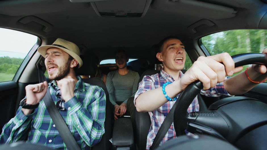 Grupo de amigos curtindo uma viagem de carro e celebrando momentos de alegria ao volante.