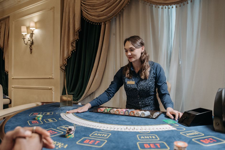 Mulher organizando fichas em uma mesa de cassino, simbolizando jogo e estratégias de apostas.