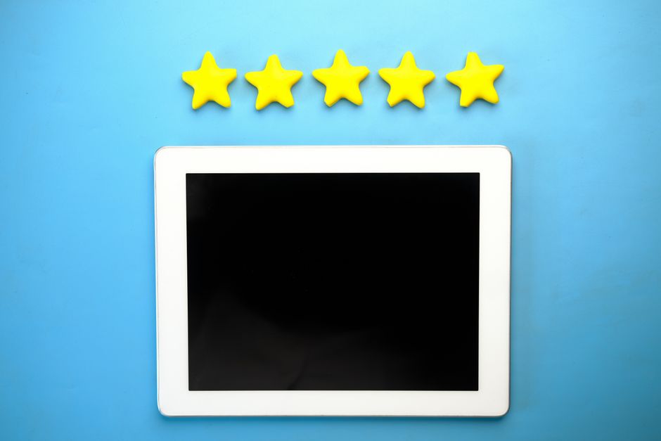 Imagem de uma tela de tablet em um fundo azul, com estrelas amarelas de avaliação acima, ideal para ilustrar temas de avaliação de satisfação ou qualidade de serviços digitais.